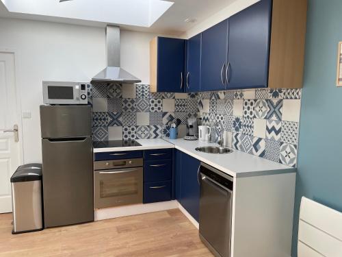 una cocina con armarios azules y electrodomésticos de acero inoxidable en l'étoile de mer - appartement le bord de mer, en Gravelines