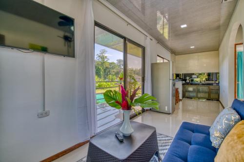 una sala de estar con un sofá azul y un jarrón de flores sobre una mesa en Oso Perezoso Pool Villa, en Puerto Viejo