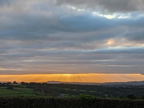 a view of the sun setting over the hills at Bespoke luxury huts with hot tubs. Located in the black mountains. in Llanveynoe