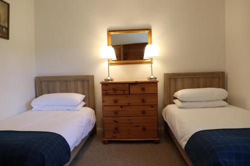 a bedroom with two beds and a dresser with a mirror at Farmston Lodge in Callander