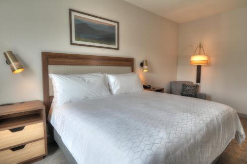 a bedroom with a white bed and a chair at Holiday Inn & Suites Pigeon Forge Convention Center by IHG in Pigeon Forge