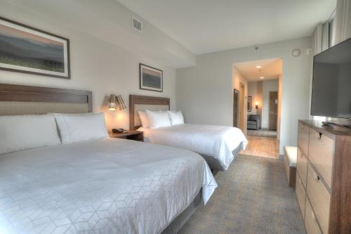 a hotel room with two beds and a flat screen tv at Holiday Inn & Suites Pigeon Forge Convention Center by IHG in Pigeon Forge