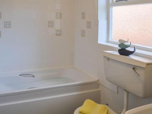 a bathroom with a tub and a sink and a window at The Cottage in Shipdham