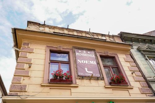 a building with two windows with red flowers on it at Pensiunea Noemi in Braşov