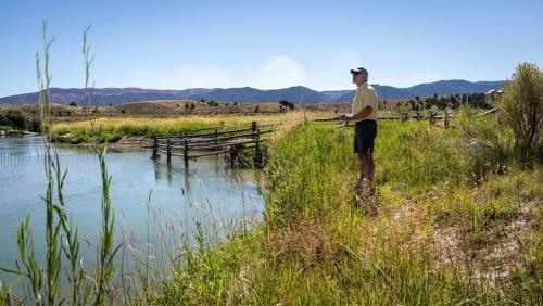 Un uomo in piedi nell'erba vicino a un fiume di The Riverside Ranch Motel and RV Park Southern Utah a Hatch