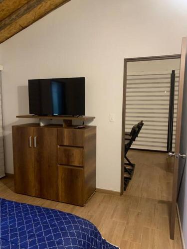 a bedroom with a tv on top of a wooden dresser at Maravilloso chalet en la zona colonial (303) in Zipaquirá