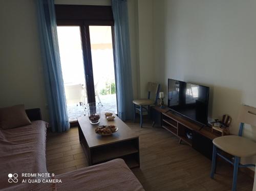 a living room with a couch and a tv at Sunset Apartment in Epanomi