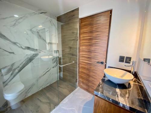 a bathroom with a glass shower and a sink at Departamento catania con vista al mar in Mazatlán