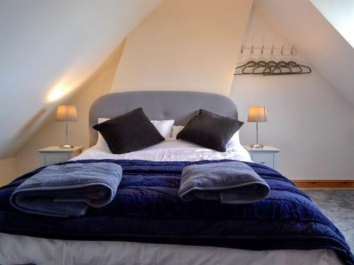 een slaapkamer met een bed met blauwe dekens en kussens bij 4 Greenhaye Cottages - Uk31236 in Newnham