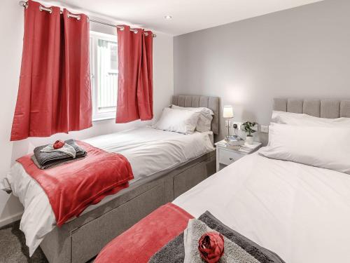 2 camas en un dormitorio con cortinas rojas en Hill Crest Lodge 1 en Hemswell