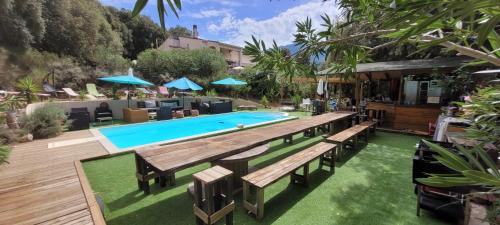 una piscina con bancos y sombrillas en un patio en Gites San Austinu en Petreto-Bicchisano