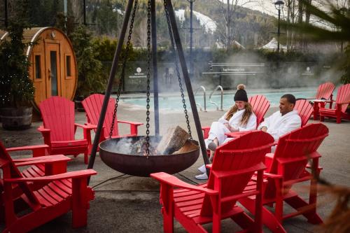 two people sitting in red chairs around a fire pit at Fairmont Chateau Whistler in Whistler