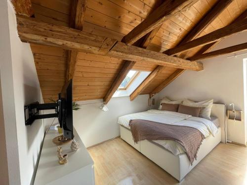 a bedroom with wooden ceilings and a bed with a tv at BullsLiving Seeapartment 2 AM CORSO in Velden am Wörthersee