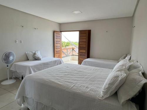 ein weißes Schlafzimmer mit zwei Betten und einem Ventilator in der Unterkunft Chalé Estrela da Barra in Barra Grande