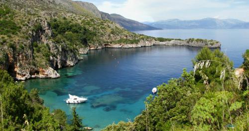 a boat in a large body of water with mountains at Hotel Calanca in Marina di Camerota