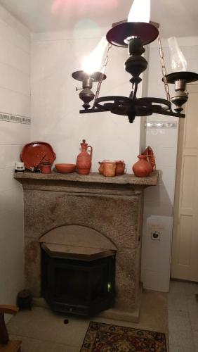 a chandelier hanging over a fireplace with pots on it at Quinta da Barbosa in Folgosinho