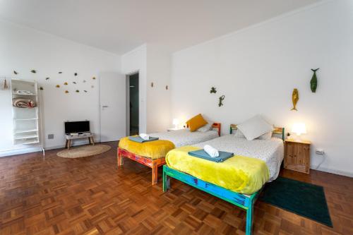 a room with two beds and a television in it at Bordallo's Lodge in Caldas da Rainha