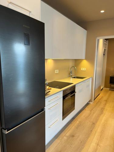 a kitchen with a black refrigerator and white cabinets at Hidden Gem in Downtown Reykjavík in Reykjavík