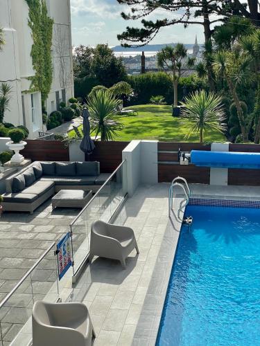 a swimming pool with chairs and a couch next to a building at The Park Hotel in Tenby