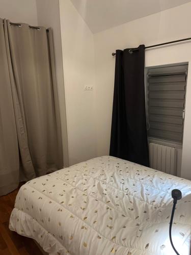 a white bed in a room with a black curtain at Studio à proximité de Laval in Soulgé-sur-ouette