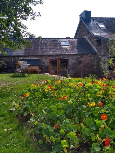 uma velha casa de pedra com flores em frente em Chaleureuse maisonnette em Lopérec