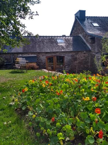 una vieja casa de piedra con flores delante en Chaleureuse maisonnette en Lopérec