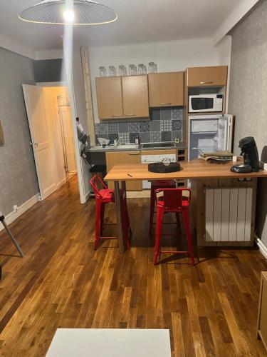 une cuisine avec une table en bois et des chaises rouges dans l'établissement Studio à proximité de Laval, à Soulgé-sur-ouette