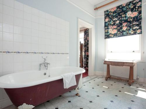 a bath tub in a bathroom with a window at Longcroft House in Torquay