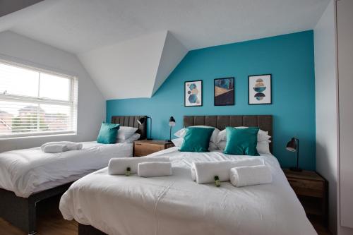 スウィンドンにあるST AUSTELL - Spacious Home, High Speed Wi-Fi, Free Parking, Gardenの青い壁の部屋にベッドが2つある
