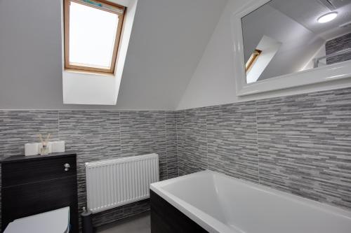 a bathroom with a white tub and a mirror at ST AUSTELL - Spacious Home, High Speed Wi-Fi, Free Parking, Garden in Swindon