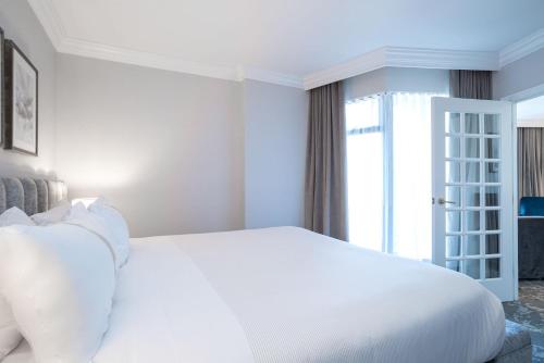a white bed in a room with a window at The Sutton Place Hotel Vancouver in Vancouver