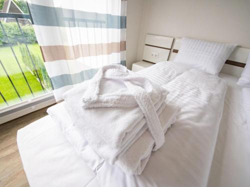une chambre avec un lit blanc avec des serviettes dessus dans l'établissement Geräumiges Ferienhaus in Damp in Strandnähe, à Damp
