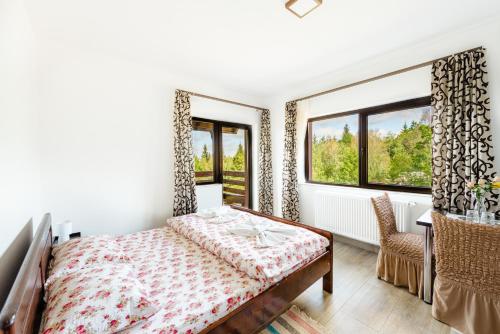 a bedroom with a bed and a table and windows at Pensiunea Agroturistica Rares in Cluj-Napoca