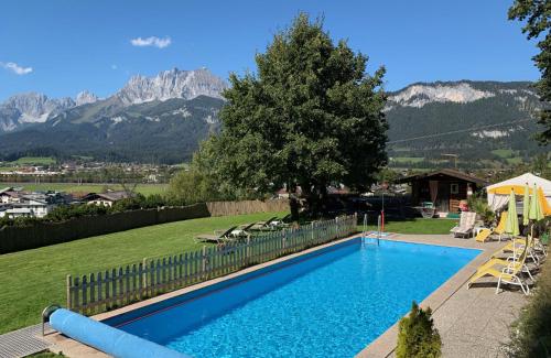 ein blauer Pool mit Bergen im Hintergrund in der Unterkunft Appartements Kaiserblick in Sankt Johann in Tirol