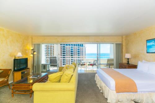 a hotel room with a bed and a couch and a balcony at Ilikai Tower 1918 Lagoon View 1BR in Honolulu