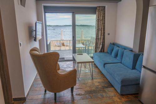 a living room with a blue couch and a view of the water at Zinozis Beach Apartments in Vourvourou