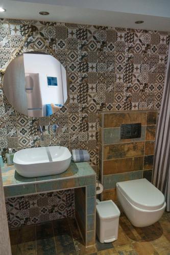 a bathroom with a sink and a toilet and a mirror at Zinozis Beach Apartments in Vourvourou
