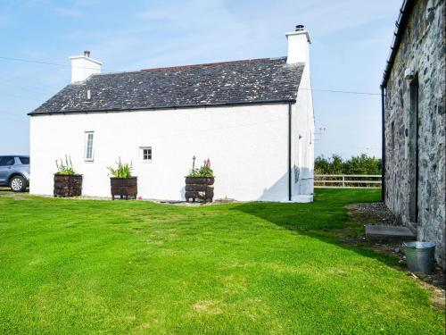 a white building with two potted plants in a yard at Ferrycroft 1 - Uk33395 in Isle of Gigha