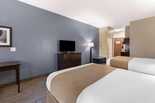 a hotel room with two beds and a flat screen tv at Best Western PLUS Fort Saskatchewan Inn & Suites in Fort Saskatchewan