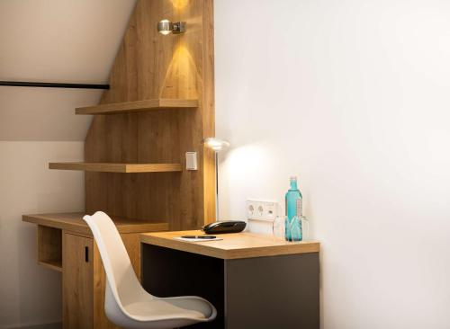 a room with a desk and a white chair at elaya hotel leipzig city center in Leipzig