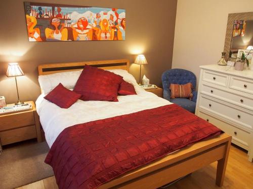 a bedroom with a bed with a red comforter at Town View in Burneside