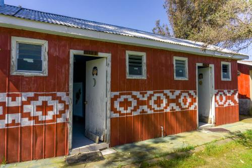 a red house with an orange and white tiled facade at Coyunche Cabañas y Camping Laja & San Rosendo in Laja