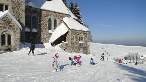 a group of people standing in the snow near a church at Hotel Zieleniec in Zieleniec