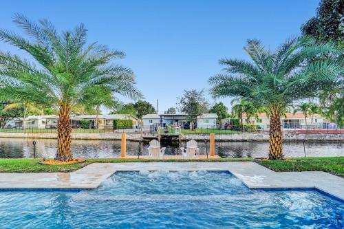 - une piscine avec deux palmiers à côté d'une rivière dans l'établissement New! Waterfront Heated Pool & Jacuzzi 2 mi to Beach - Fishing Pier Relaxing SPA & Hammock, à Fort Lauderdale