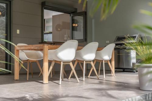 a dining room table and four white chairs at The Mac in Smiths Lake