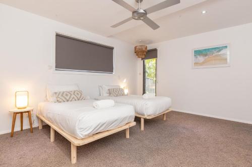 two beds in a room with a flat screen tv at The Mac in Smiths Lake