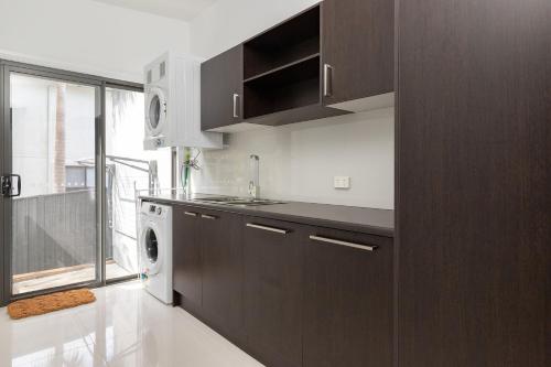 a kitchen with brown cabinets and a washer and dryer at The Mac in Smiths Lake