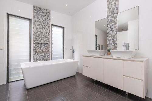 a white bathroom with two sinks and a tub at The Mac in Smiths Lake