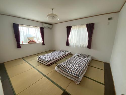 two beds in a room with two windows at 琵琶湖畔澄の宿 in Otsu