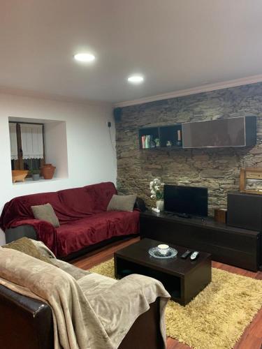 a living room with a red couch and a stone wall at Casa do Soto in Milhão